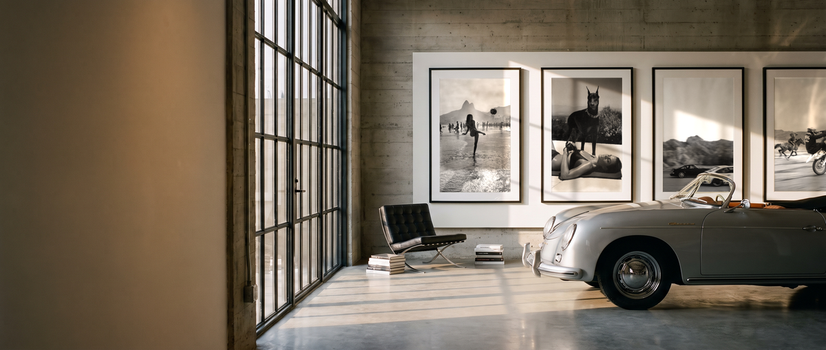 Gallery loft with framed prints and a vintage roadster in late-afternoon light